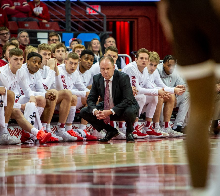 Greg Gard squats in front of his bench, including some Badger Freshmen