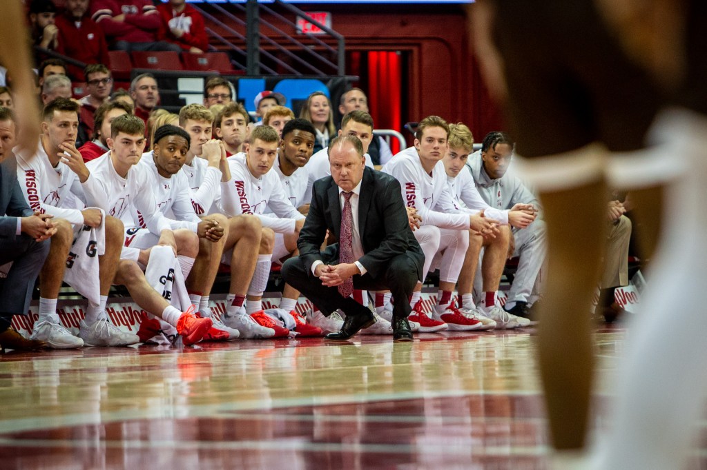 Greg Gard squats in front of his bench, including some Badger Freshmen