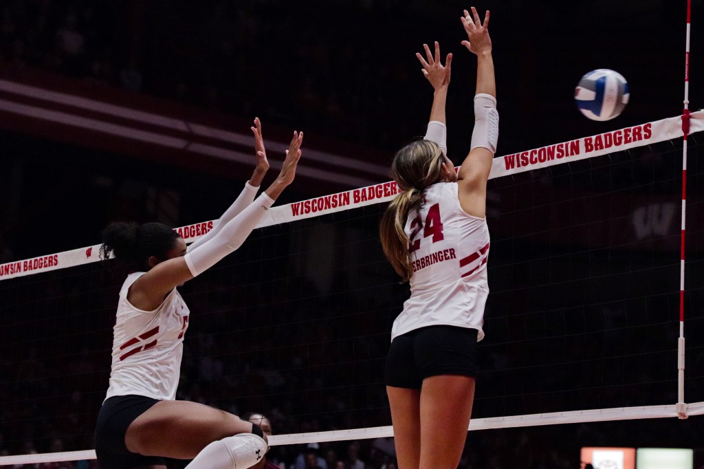 Charlie Fuerbringer jumps with both arms straight up in the air while Carter Booth jumps to her left.