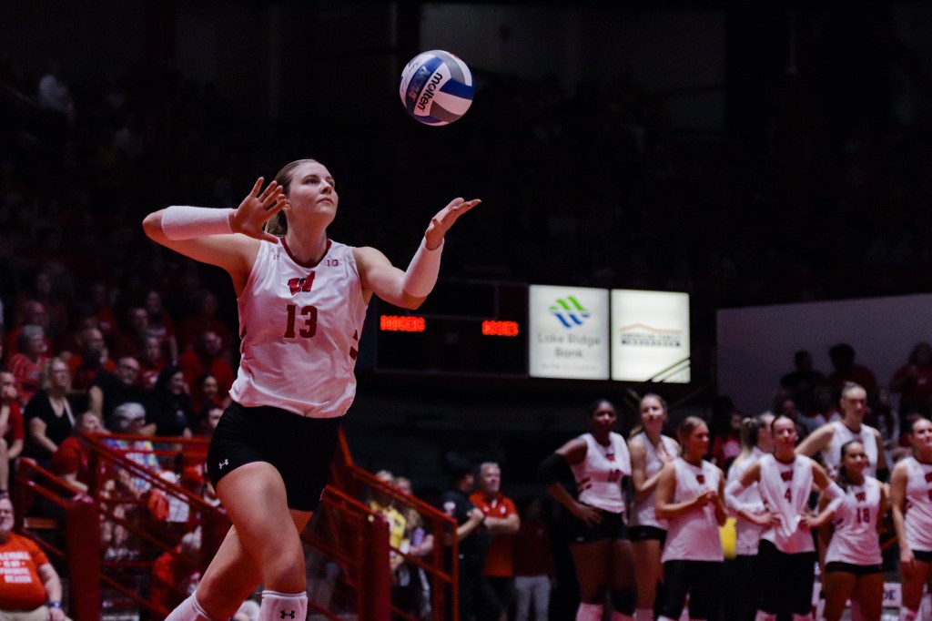 Sarah Franklin tosses the ball in the air with her arm ready to swing and serve the ball.