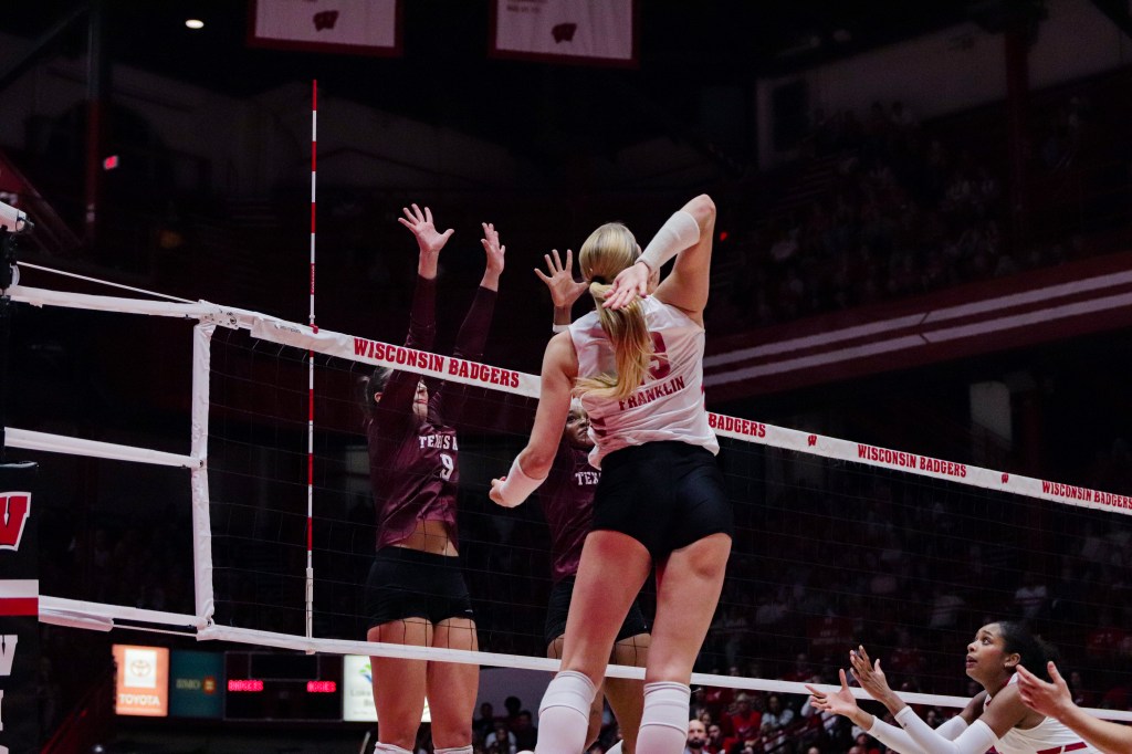 Sarah Franklin raises her arm back to attack a ball while Texas A&M defenders jump behind the net.