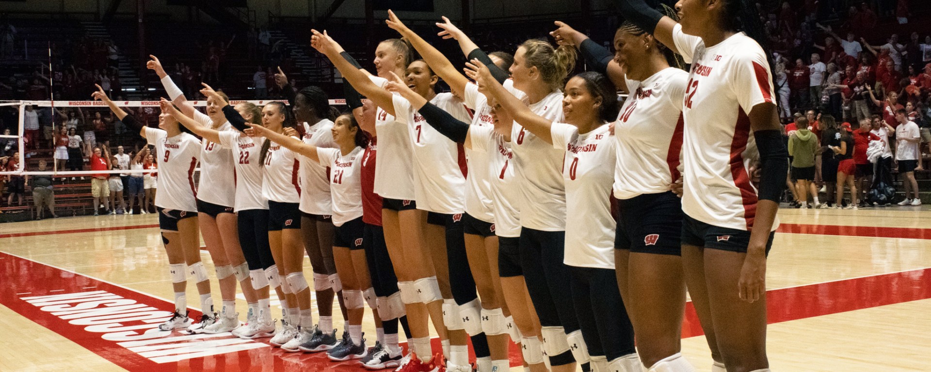 Badger volleyball players lined up facing the crowd as they sing "Varsity."