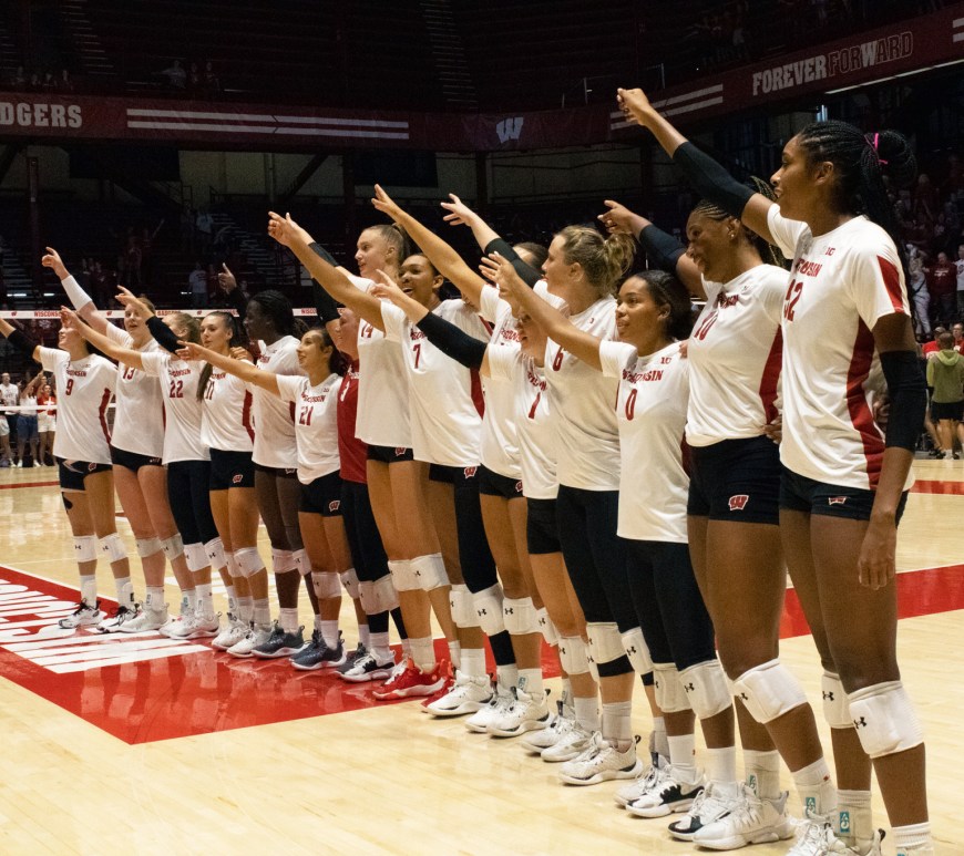 Badger volleyball players lined up facing the crowd as they sing "Varsity."