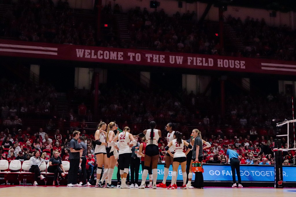 The Badgers stand in a circle and listen to a coach.